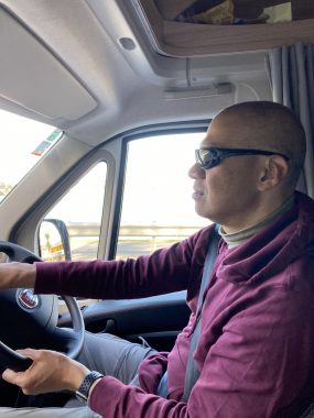 activities for patients and caregivers | Amyloidosis News Today | Jaime's husband, Aubrey, wears sunglasses and a maroon sweatshirt while driving the car.
