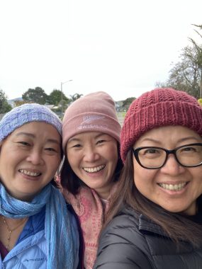 true friend | Amyloidosis News Today | Jaime smiles outside with two of her friends during a road trip. All three women are wearing beanies and warm jackets.